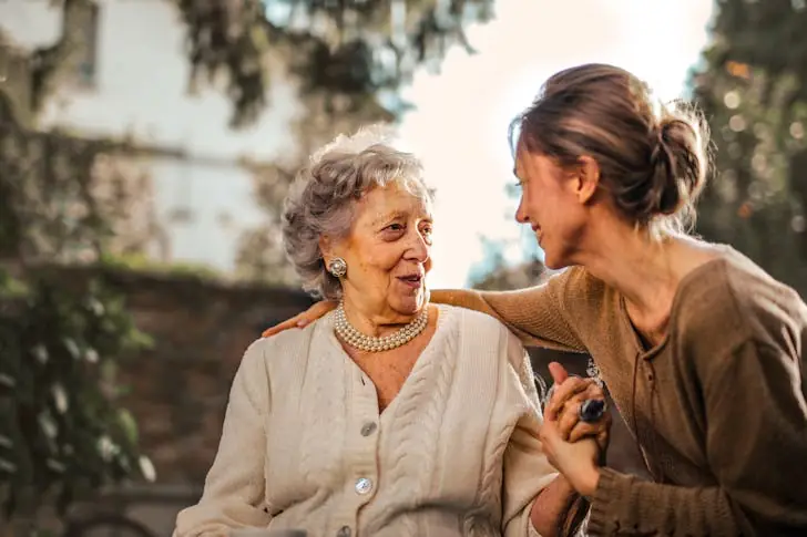 Advice from old people- a young woman being kind to a senior in the garden.